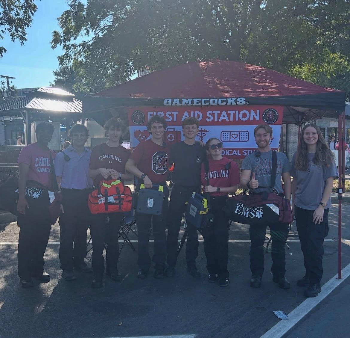 Gamecock EMS crew standing in front of a Gamecocks First Aid Station tent