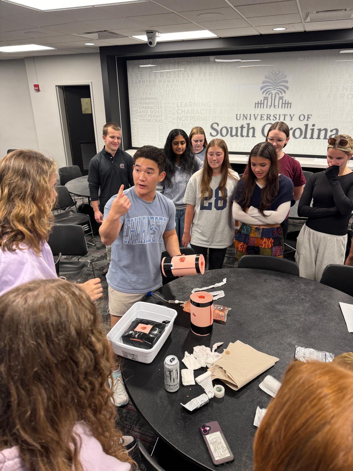Gamecock EMS member demonstrating wound packing to a group of students