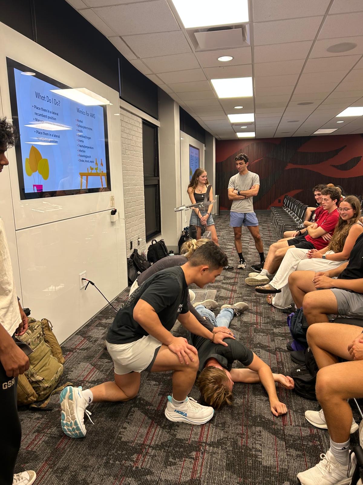 Members practicing recovery position during a training lecture
